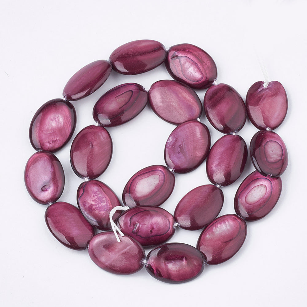 Dyed oval shell bead strand in rosy mauve, glossy beads arranged in a loop