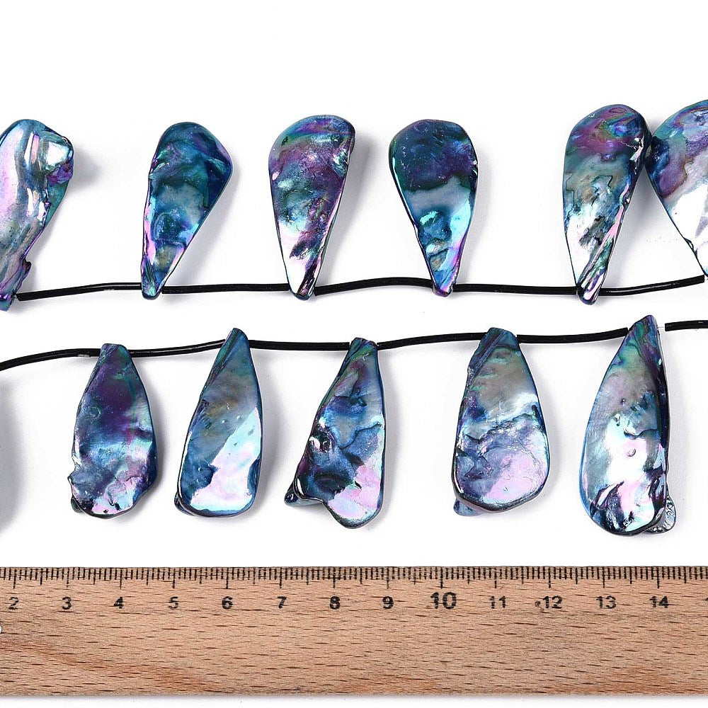 Teardrop shell bead strand on black cord beside a ruler, iridescent blue-purple beads