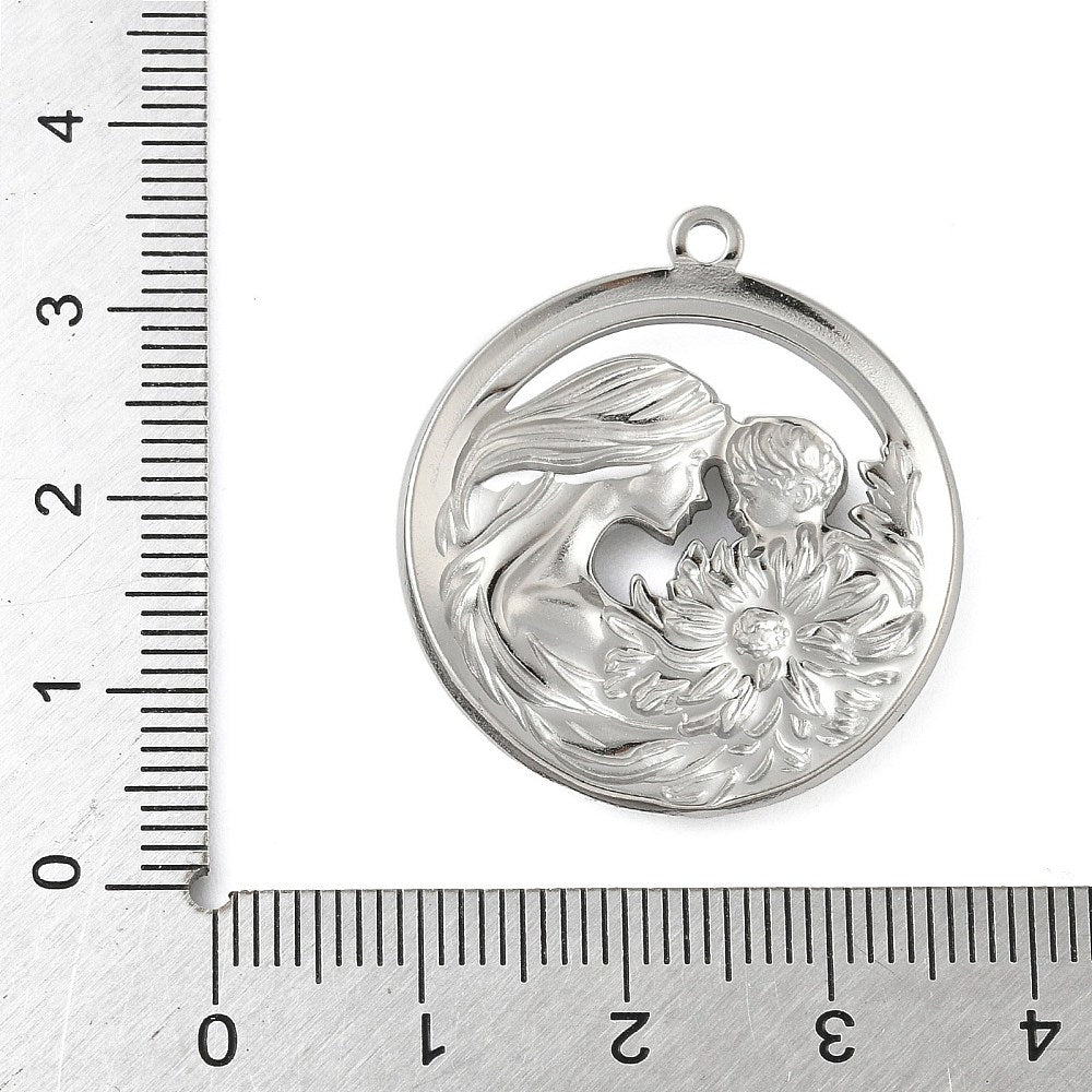 Round silver mom and baby pendant with floral relief, shown against measurement ruler