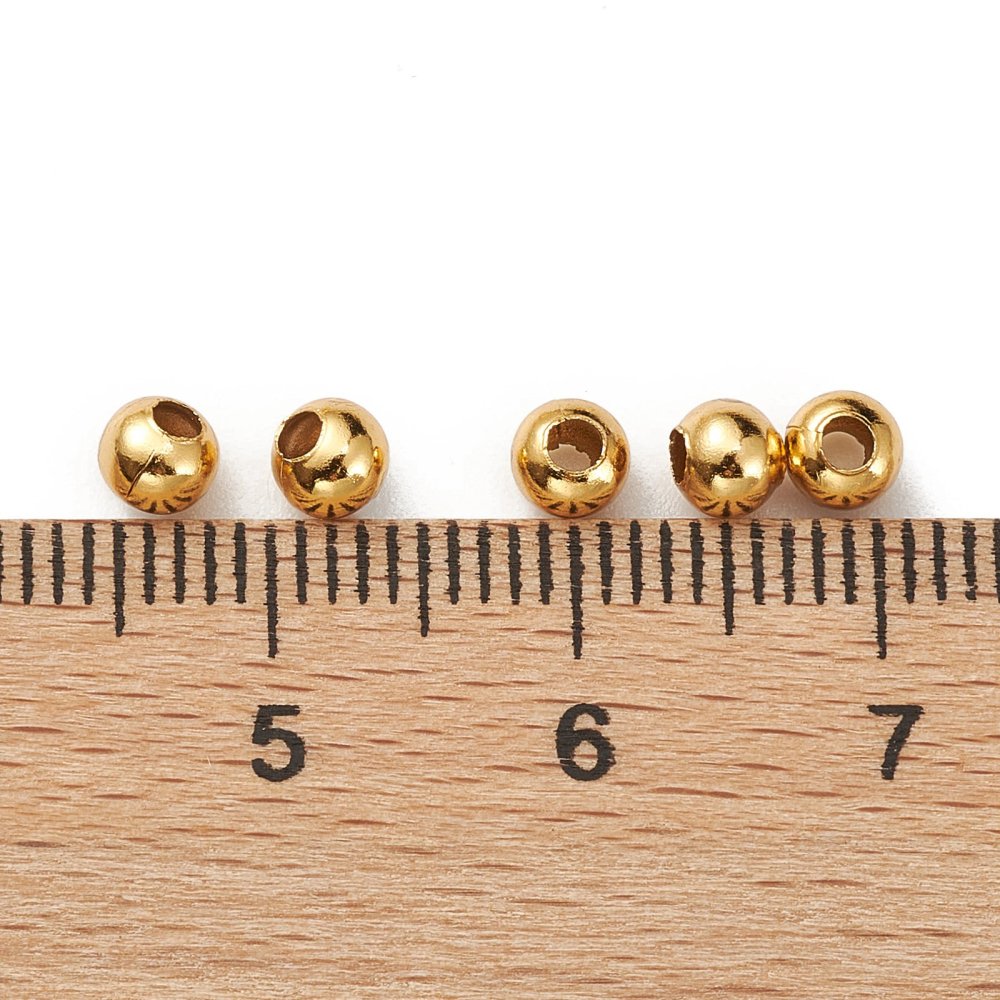 Gold-plated round beads aligned on a ruler, showing 4mm length