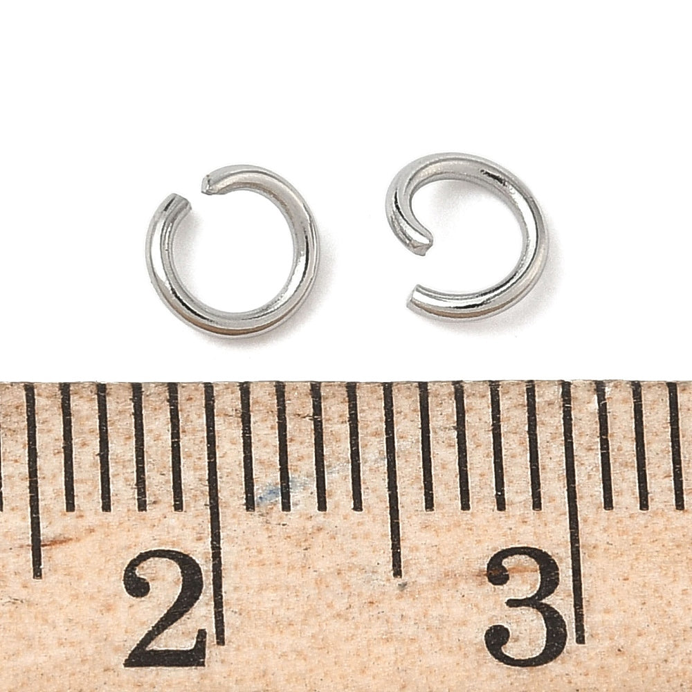 Open silver stainless jump ring beside measuring ruler for size reference