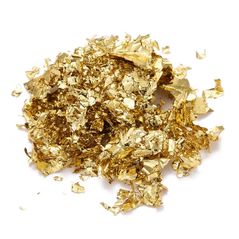 Gold metallic foil flakes piled on a flat surface
