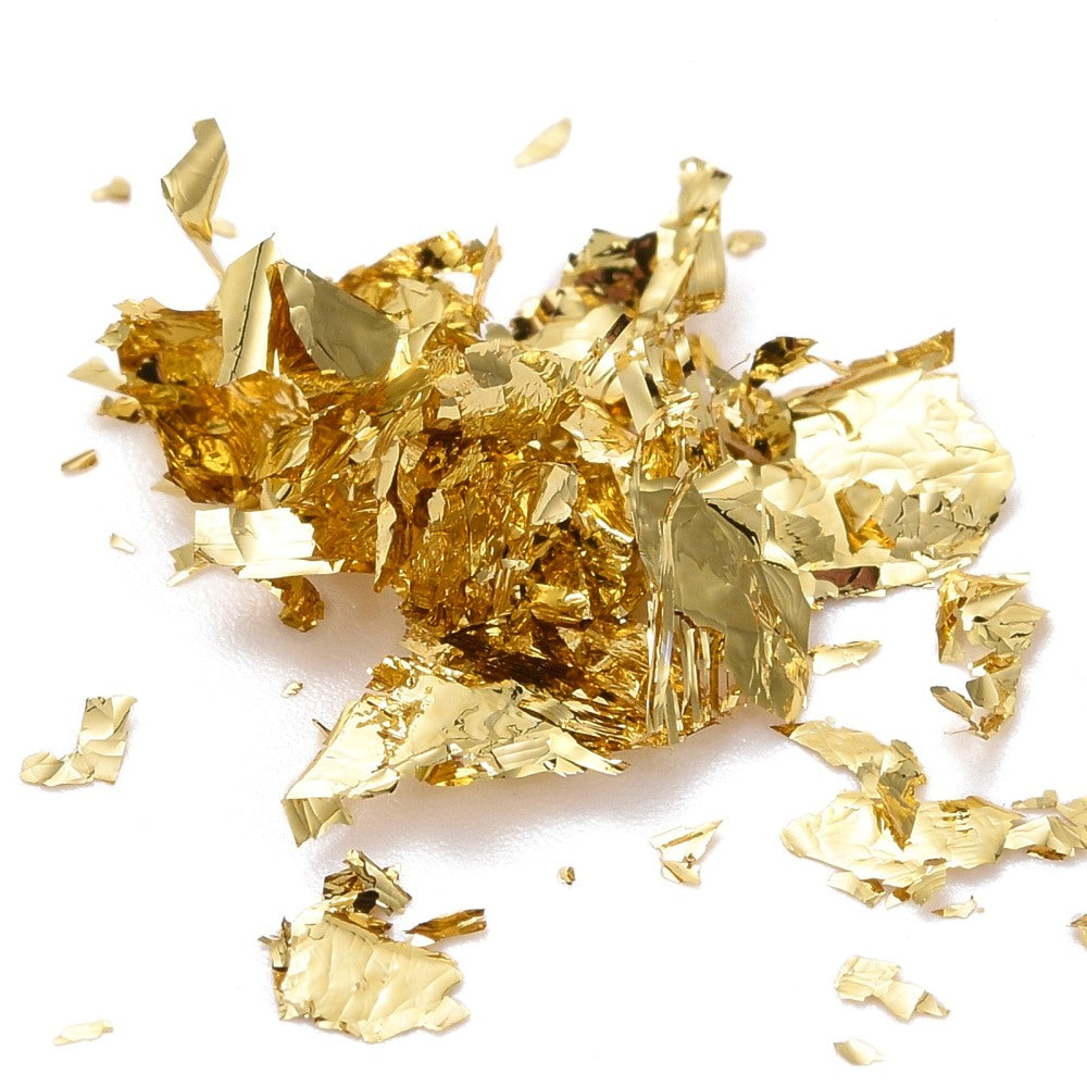 Gold metallic foil flakes scattered across a flat surface