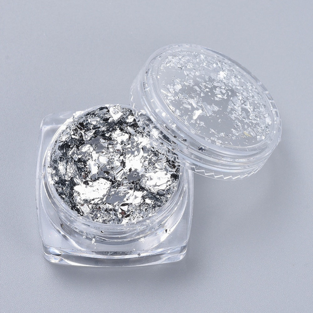 Silver foil flakes in two clear jars, one with larger reflective chunks
